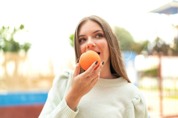 Young pretty blonde woman holding an orange with happy expression - Fotoğraf, Görsel