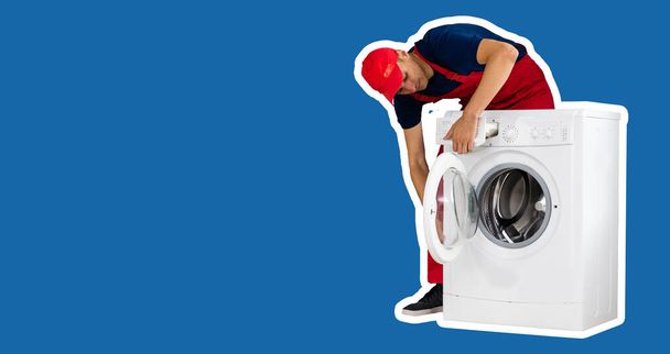 The repairman in worker suit with the professional tools box is fixing the washing machine on a blue background. - Valokuva, kuva