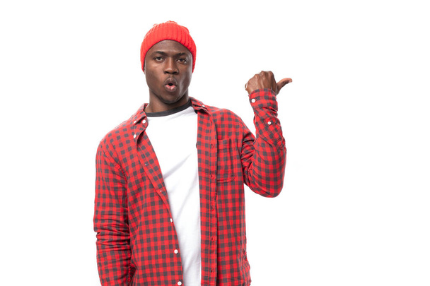 confident young ethnic african guy in red plaid shirt and jeans gesturing over isolated white background. - Photo, Image