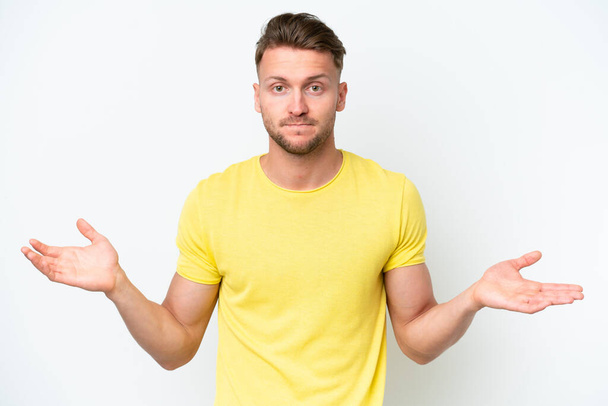 Young blonde caucasian man isolated on white background having doubts while raising hands - Photo, Image