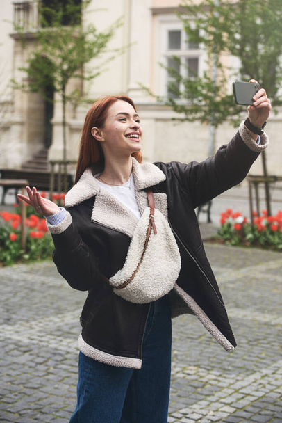 femme heureuse communique avec des amis via lien vidéo à l'extérieur sur une rue de la vieille ville. - Photo, image