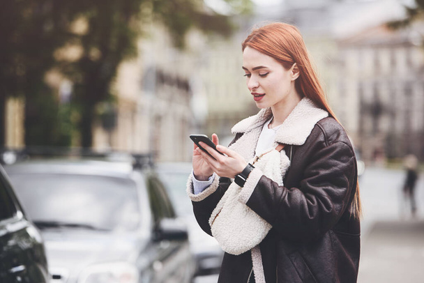 gelukkig vrouw communiceert met vrienden via video link buiten op een oude stad straat. - Foto, afbeelding