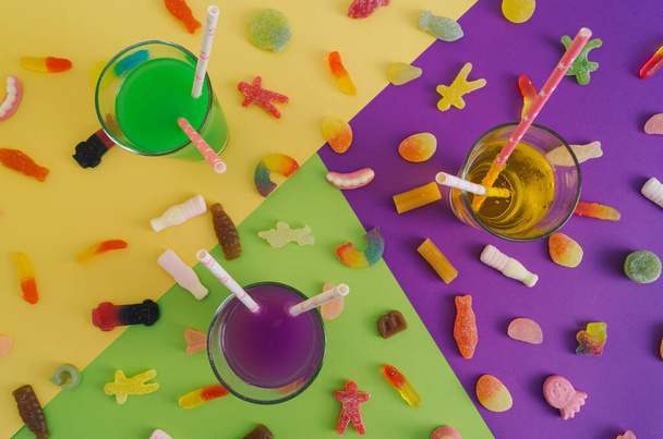 Colorful party cocktails and sweet gummy candies on yellow, green and violet background. Flat lay summer party concept. - Zdjęcie, obraz