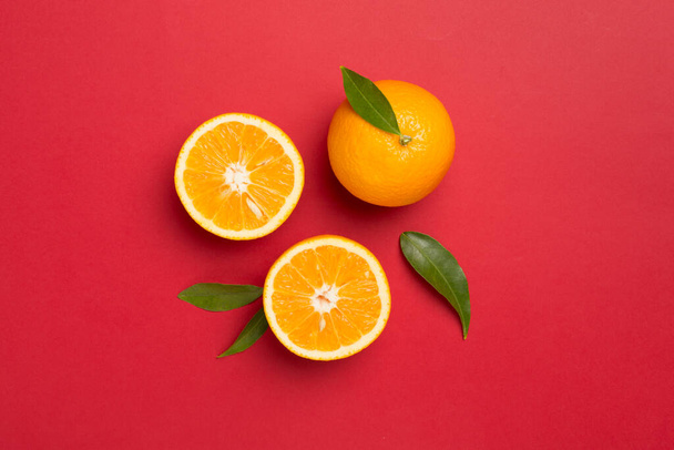新鮮なオレンジと色の背景に葉でフラットレイアウト. - 写真・画像