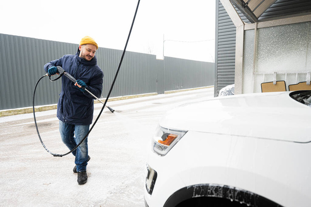 Man washing high pressure water american SUV car at self service wash in cold weather. - Photo, Image