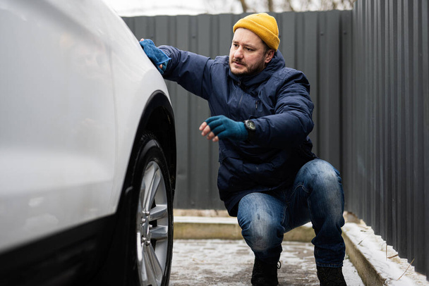 Man wipes american SUV car with a microfiber cloth after washing in cold weather. - Φωτογραφία, εικόνα
