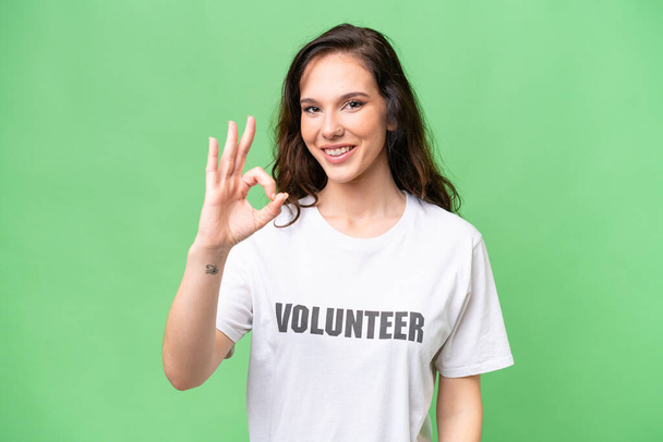 Giovane volontario donna caucasica su sfondo isolato mostrando segno ok con le dita - Foto, immagini