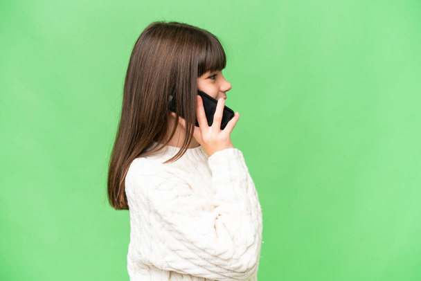 mała kaukaska dziewczyna na odosobnionym tle prowadzenie rozmowy z telefon komórkowy z kimś - Zdjęcie, obraz