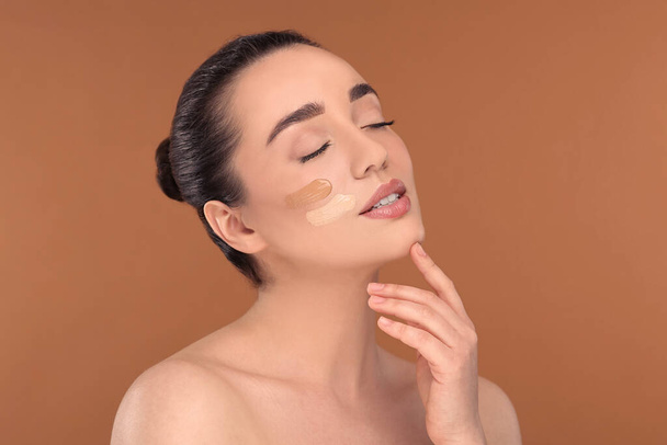 Woman with swatches of foundation on face against brown background - Foto, Imagem