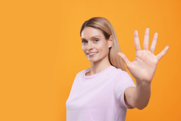 Woman giving high five on orange background, space for text - Foto, imagen