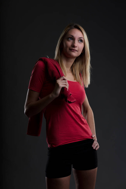 Portrait of a girl in gym attire: red t-shirt, black leggings. Effort is key, both physically and mentally. Determined to achieve results, she works hard, leaving no room for magic - Fotografie, Obrázek
