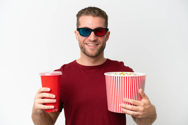 Nuori valkoihoinen mies pitelee popcornia ja soodaa eristyksissä valkoisella pohjalla - Valokuva, kuva