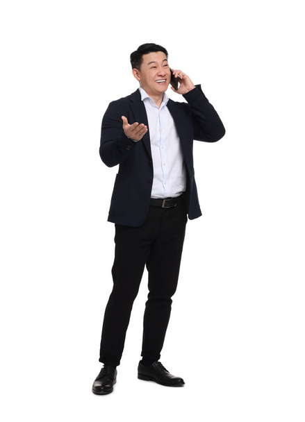 Businessman in suit talking on phone against white background - Fotografie, Obrázek
