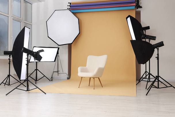 Interior do estúdio de fotografia moderna com poltrona e equipamento de iluminação profissional - Foto, Imagem