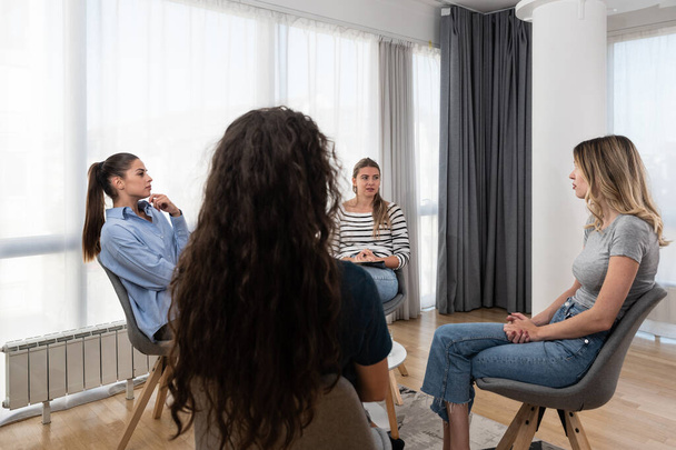 Happy positive smiling female coach, therapist or business team manager supporting and motivating young women in group therapy session or corporate staff training meeting at work - Photo, Image