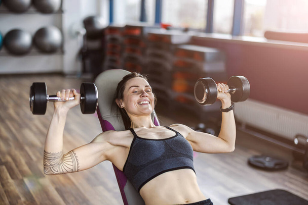 Mujer joven haciendo ejercicio con pesas en un club de salud - Foto, Imagen