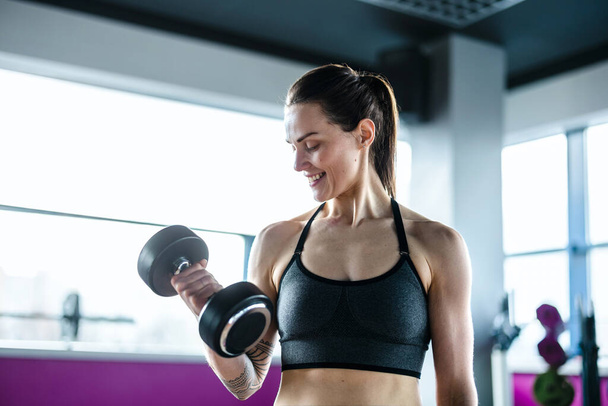 Young woman exercising with dumbbells in a health club - Foto, afbeelding