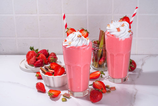Rhabarber und Erdbeer-Milchshake oder Smoothie, erfrischendes Sommergetränk, Gesunde Ernährung und antioxidative Sommergetränke mit Schlagsahne, frischem Rhabarber, Erdbeerscheiben, auf weißem Küchentisch - Foto, Bild