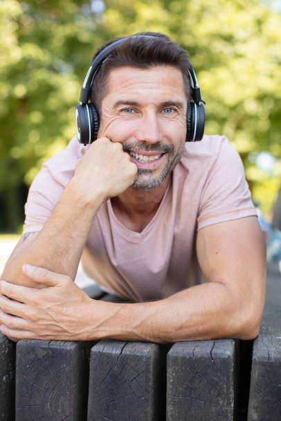 happy man listening to music on a bench outdoors - 写真・画像