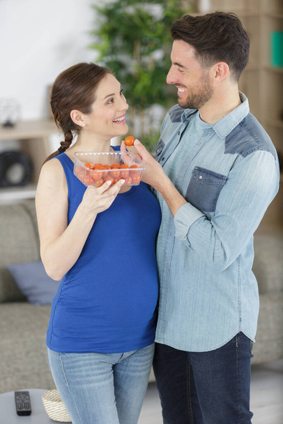 pregnant couple with tomatoes in the kitchen - Foto, Bild