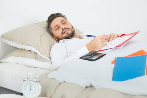 exhausted businessman sleeping in bed in hotel room - Foto, Imagen