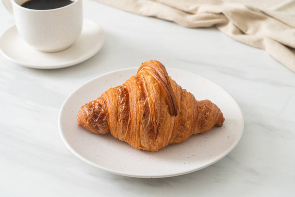 fresh croissant on white plate with black coffee - Foto, imagen