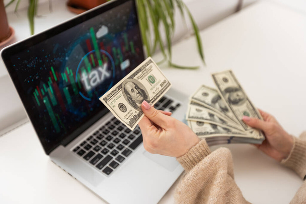 Financieel concept. Geld verdienen op het internet. Vrouw zit en werkt met een laptop. - Foto, afbeelding