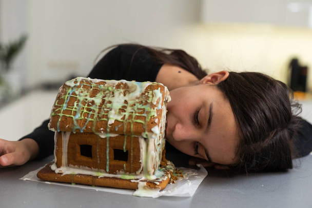 Kids with gingerbread house, A teenage girl is eating a gingerbread house. - Foto, Imagem