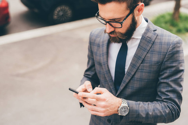 Young bearded elegant businessman outdoors using smartphone - Фото, изображение
