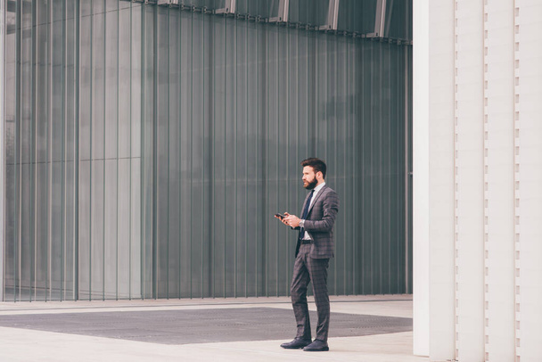 Впевнений і професійний елегантний бородатий бізнесмен позує на відкритому повітрі сильний і стійкий
 - Фото, зображення