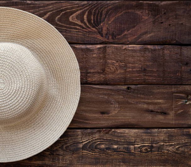 половина верхнего вида соломенной пляжной шляпы на деревянном фоне. Пространство для текста - Фото, изображение