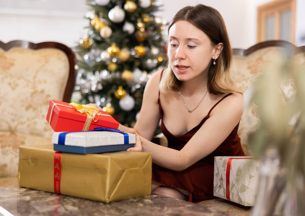 Young woman, being in anticipation of the holiday, prepares Christmas presents for guests at home - Foto, Imagem