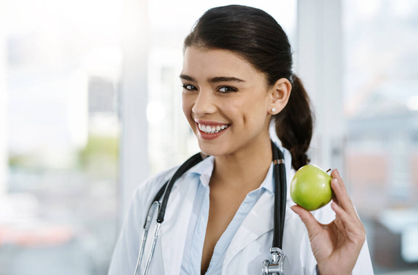 Doctor, portrait and happy woman with apple for nutrition, healthy diet or wellness. Face, nutritionist or medical professional with fruit for advice, healthcare or natural food for vegan benefits. - Fotografie, Obrázek
