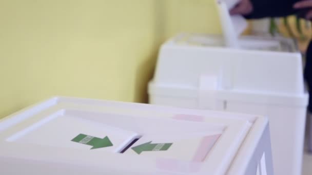 Hands of people drop ballots in box - Video