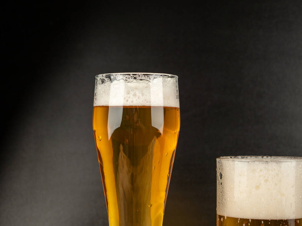 Ein Glas kaltes Bier auf dunklem Hintergrund. Glas Bier aus nächster Nähe. - Foto, Bild