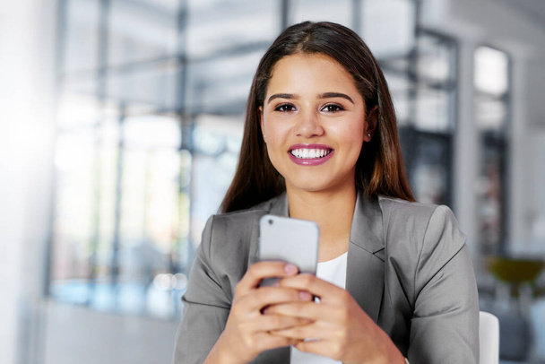 Its one way to stay updated. Cropped portrait of a young businesswoman texting on a cellphone in an office - Foto, Imagem