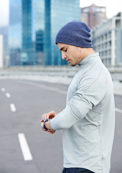 Rush hour is a long way off. a young jogger checking the time while out for a run in the city - Foto, imagen