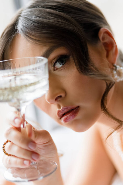 Κοντινό πορτραίτο μιας νεαρής γυναίκας με ένα ποτήρι σαμπάνια κοντά στο πρόσωπό της. Υψηλής ποιότητας φωτογραφία - Φωτογραφία, εικόνα
