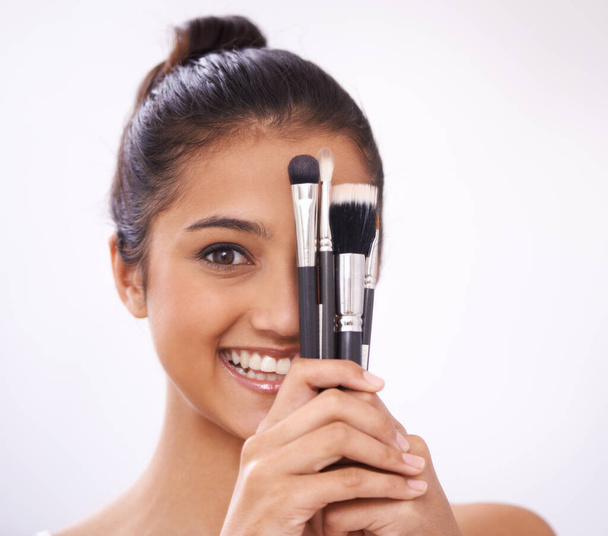 Shes a great makeup artist. A young woman holding makeup brushes against her face - Zdjęcie, obraz