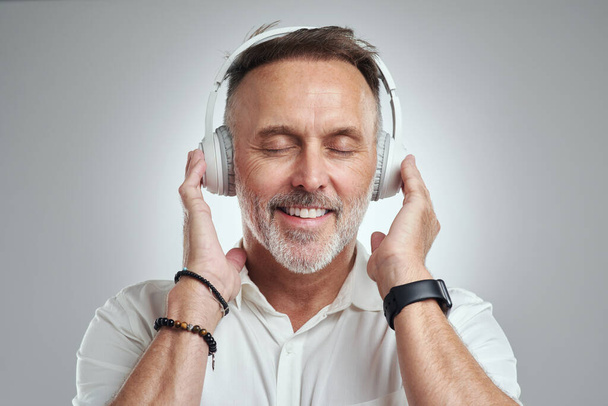 Music calms the chaos in my head. Studio shot of a mature man wearing headphones against a grey background - Foto, Bild