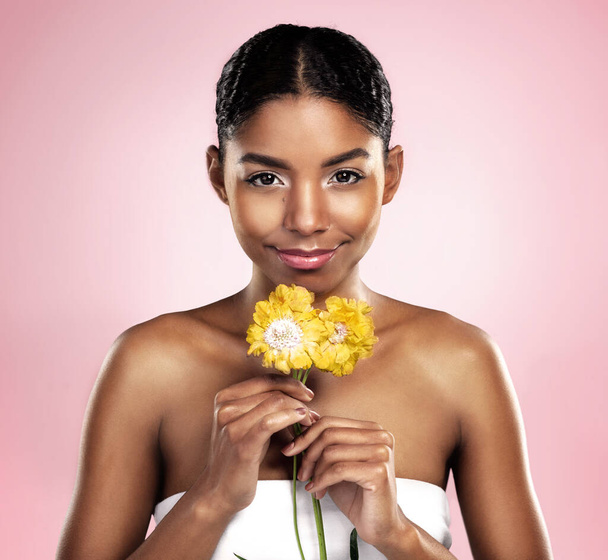 Portrait, woman and flowers for skincare in studio, pink background and eco friendly cosmetics. Face, african model and natural beauty with yellow daisy, plants and sustainability for floral blossom. - Photo, Image