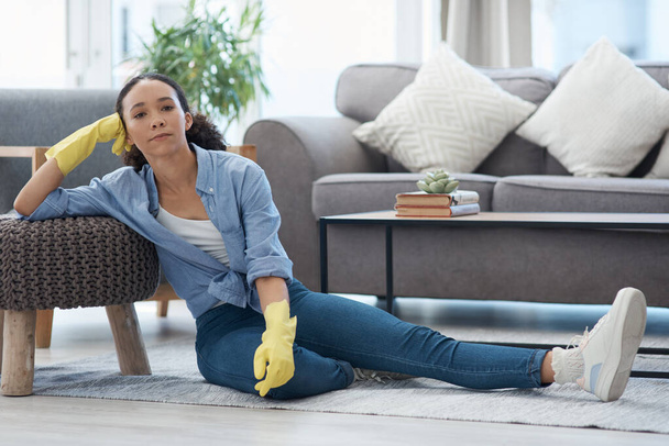 Woman, portrait and cleaner relax after cleaning living room, housekeeping and tired housekeeper at home. Serious female person on break, clean house with hygiene and gloves for safety from bacteria. - Photo, Image