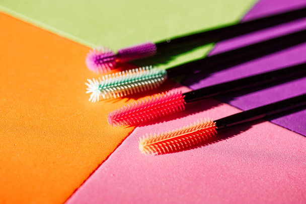 Set of multicolored silicone mascara brushes on a multicolored bright background. Green, pink, purple, orange lash brushes. Modern decorative cosmetics for women. Female beauty and glamour fashion.  - Photo, Image