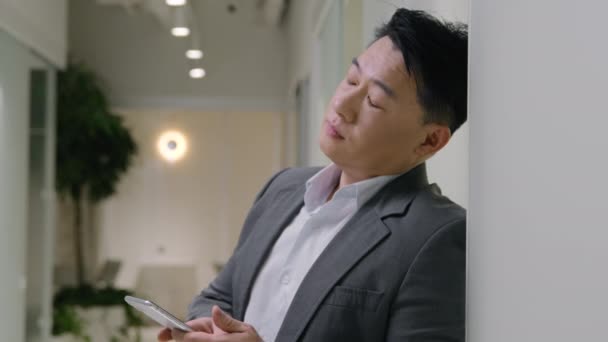 Fatigué bouleversé asiatique mature homme épuisé 40s chinois homme d'affaires surmené problème de téléphone mobile recevoir un mauvais message fatigué entrepreneur masculin dans le couloir de bureau se sentent désespoir surcharge téléphone portable app problème - Séquence, vidéo