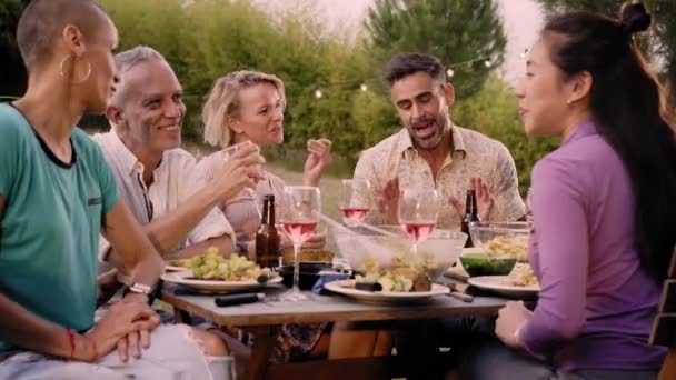 Šťastnou rodinu, jak jí a pije červené víno na večírku u večeře. Starší a mladí lidé spolu večeří na dvorku. Mládež a starší víkendové aktivity životního stylu. Kvalitní fotografie - Záběry, video