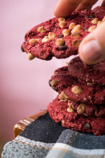 手は木製テーブルの上にチップと赤いチョコレートクッキーを取ります - 写真・画像