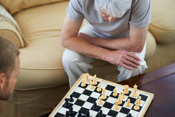 Its all about the strategy. High angle shot of a father and son playing a game of chess together at home - Foto, Imagen