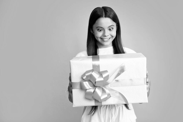 Teenager kid with present box. Teen girl giving birthday gift. Present, greeting and gifting concept. Surprised face, surprise emotions of teenager girl - Foto, immagini