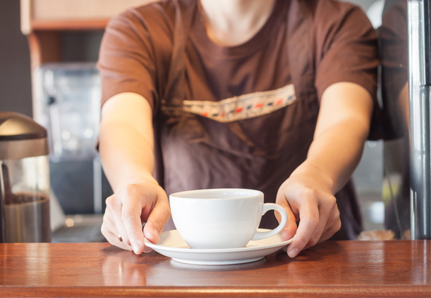 Barista biedt witte kop koffie - Foto, afbeelding