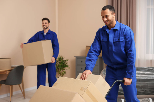 Male movers with cardboard boxes in new house - Fotografie, Obrázek
